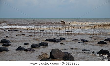 Fierce Waves On The Beach That Hit The Black Coral With Selective Focus.