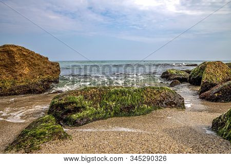Dey View Of A Beautiful Seascape With A Close View Of Stone With Moss. Blurred Background.
