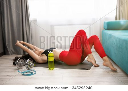Young Fit Brunette Woman In Sportwear Lies On The Floor Looking Tired After Daily Home Workout On Th