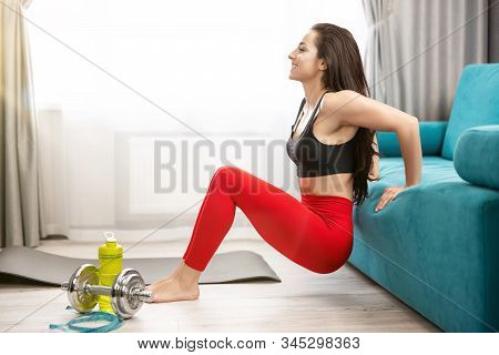 Fit Brunette Woman In Red Leggings And Black Top Doing Everyday Warm Up Home Exercises On The Floor,