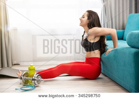 Fit Brunette Smiling Woman In Red Sport Leggings And Black Top Doing Everyday Warm Up Home Exercises