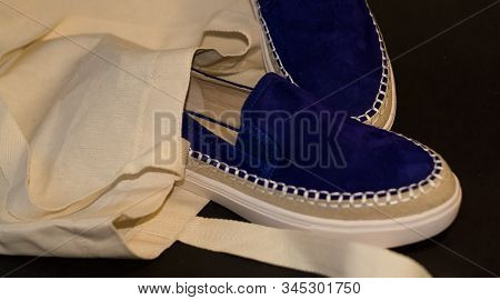 On Black Background Of The Shopping Bag, Shopper, Of Beige Cloth And Blue Slipons Of Suede. Street F