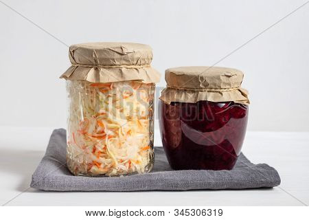 Homemade Sauerkraut With Carrots And Cabbage Salad With Beets In A Glass Jar On A White Wooden Backg