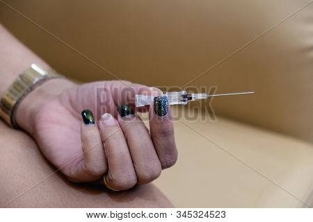 The Hand Of A Woman With Beautiful Nails Holding The Needle In Your Hand To Wait For Treatment