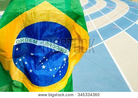Athlete Wearing Brazilian Flag Against A Blue And Tan Running Track Background