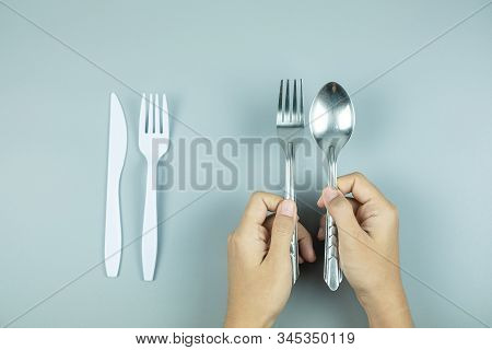 Man Holding Stainless Steel Spoon And Fork Over White Plastic Tool. Environmental Protection, Zero W