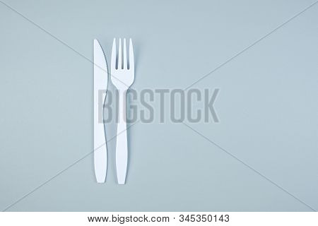 White Plastic Fork And Knife On Gray Background With Copy Space For Text. Environmental Protection, 