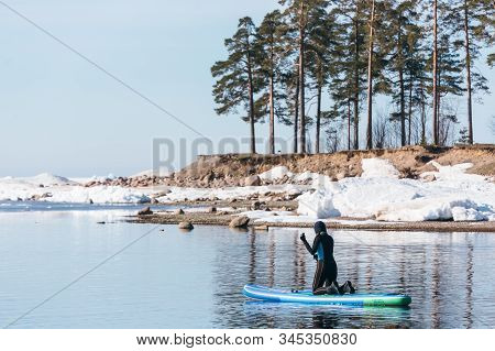 Unrecognizable Woman Wearing A Wetsuit Stay On Her Knees On A Sup Board And Paddle. Female Floating 