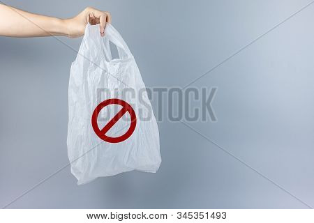 Man Holding Plastic Bag Against Gray Background With Copy Space For Text. Environmental Protection, 