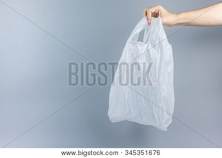 Man Holding Plastic Bag Against Gray Background With Copy Space For Text. Environmental Protection, 