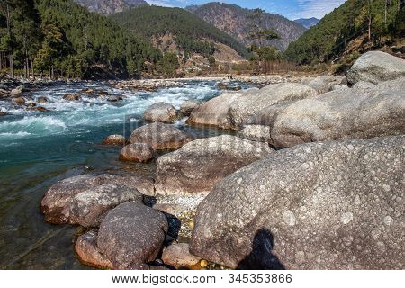 A Small Creek Flowing Through The Valleys Of The Himalayan Mountains With Big Rocks And Pebbles