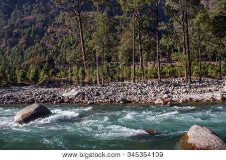 A Small Creek Flowing Through The Valleys Of The Himalayan Mountains With Big Rocks And Pebbles