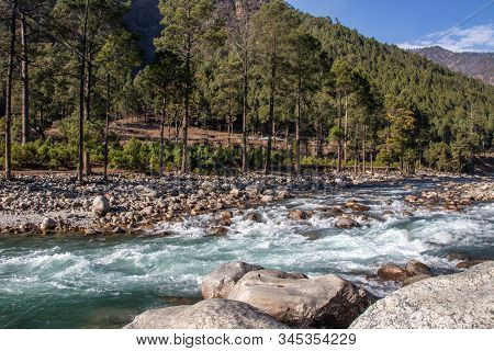 A Small Creek Flowing Through The Valleys Of The Himalayan Mountains With Big Rocks And Pebbles