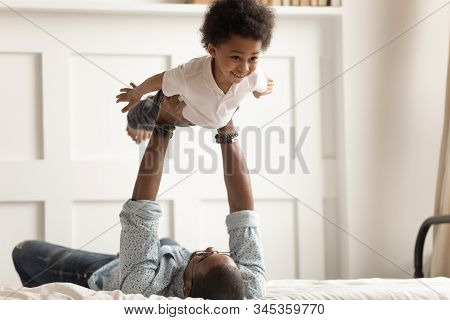 Cute Funny Black Boy Flying In Strong Fathers Hands.