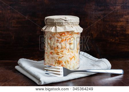 Homemade Sauerkraut With Carrots In A Glass Jar On A Dark Wooden Background. Fermented Food. Marinat
