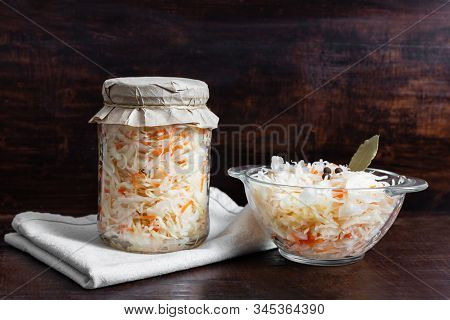 Homemade Sauerkraut With Carrots In A Glass Jar And Bowl On A Dark Wooden Background. Fermented Food
