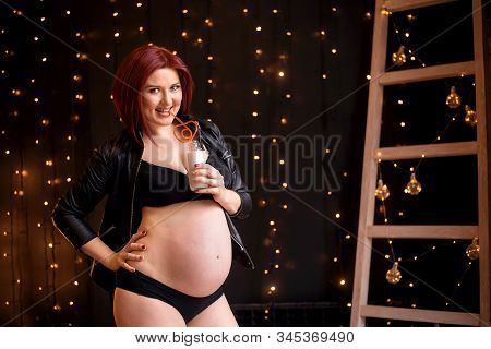 Smiling Audacious Pregnant Beautiful Woman About 26 Weeks In Lingerie And Jacket Standing And Drinki
