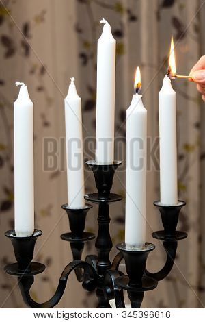 Burning Candles In Retro Candlestick Stands On Table In Room. Woman Hand Lights Candles. Romantic At