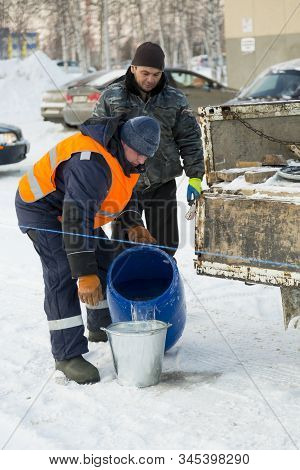 Worker Pours Water From A Barrel Into A Bucket
