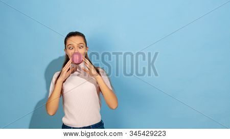 Inflating Bubble Of Gum. Caucasian Teen Girls Portrait On Blue Background. Beautiful Model In Casual