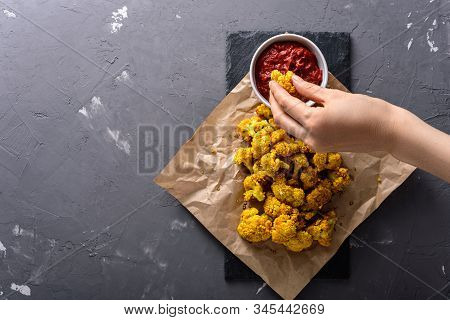 Top View Hand Dips Cauliflower In Sauce On Black Background