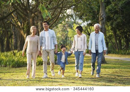 Three Generation Happy Asian Family Walking Outdoors In Park