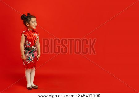 Posing Confident And Smiling. Happy Chinese New Year 2020. Asian Cute Little Girl Isolated On Red Ba
