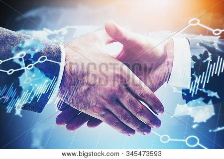 Close Up Of Two Businessmen Shaking Hands Over Blue Background With Double Exposure Of Blurry World 