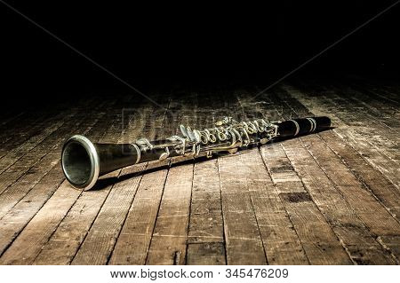 Black Woodwind Clarinet Lies On A Brown Wooden Stage