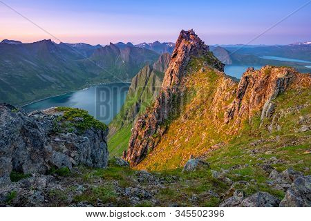 Dawn Norwegian Sun Illuminates The Top Of Mount Husfjellet Warm Light, And The Bottom Stretches Blue
