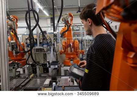 Young Man Programming Industrial Automatic Robot In Automotive Industry