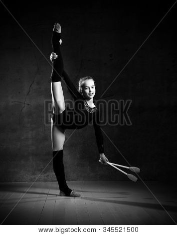 Balck And White Phoro Of Girl Gymnast In Black Sport Body And Uppers Standing Sideways And Holding T