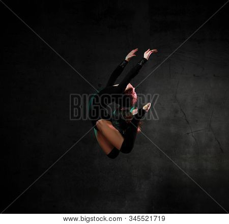 Cool Sporty Girl Gymnast In Black Sport Body And Uppers Jumping And Making Dymnastic Pose In Air Ove