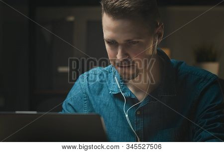 Persistent Young Man With Earphones Working At Laptop Indoors, Concentrating And Deep In Thought Whi