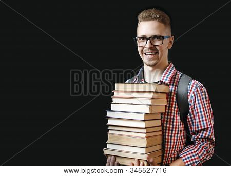 Happy Student With Glasses And Backpack Holding Lots Of Textbooks Isolated On Black Background