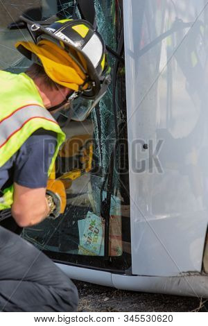Vertical Shot Of Mergency Responder Sawing Through A Mini Van Window At Accident Site