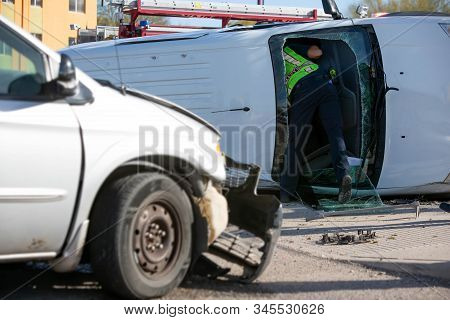 Emergecy Responder Leaning In To Clear The Contents Of A Crashed Mini Van