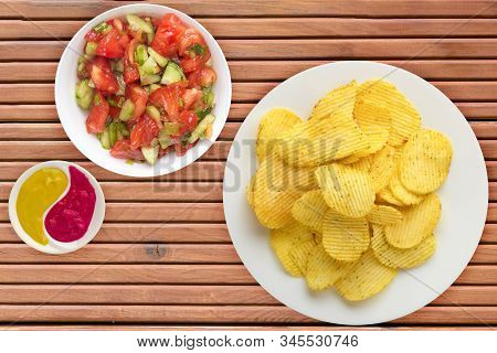 Potato Chips On A White Plate With Vegetarion Salad. Chips On A Orange Wooden Background Top View.