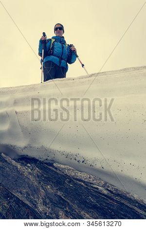 Female Mountaineer Standing On Top Of Melting Snow Ridge.
