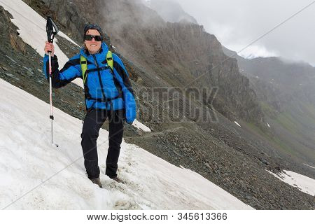 Female Mountaineer Standing On A Snowy Slope In The Mountains.