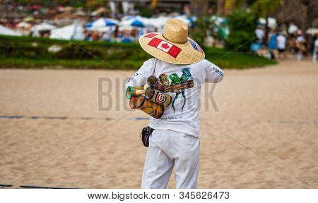 Mexican Street Vendor Selling Straw Handbags And Hats On The Waterfront, Malecon, In Puerto Vallarta