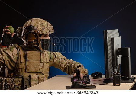 Military In Uniform Sitting At A Computer Are Cyberwar, Playing, Throwing A Grenade