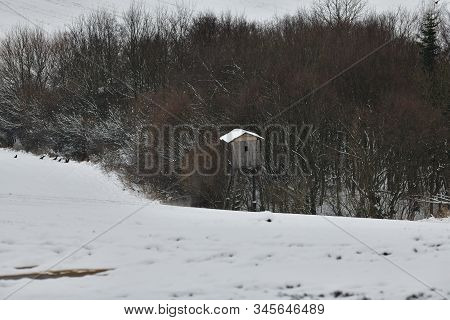 Wooden hunting lodge for hunting in the meadow in winter