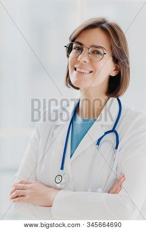Close Up Portrait Of Short Haired Female General Practitioner Stands With Smile And Arms Crossed, Us