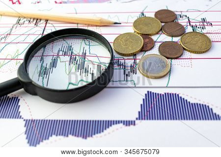 Magnifier With Coins (euro) And A Pencil On A Chart Backround. Finance Content.