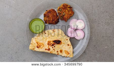 Hydrabadi Kawab Paratha With Green Chili Sauce & Onion On Transparent Plate. Kabab An Irani Dish Wit