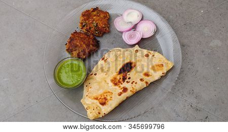 Hydrabadi Kawab Paratha With Green Chili Sauce & Onion On Transparent Plate. Kabab An Irani Dish Wit