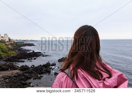 A Young Lady Enjoying The Nature Scenery At Jeju Yongduam Rock, Jeju Island, South Korea.