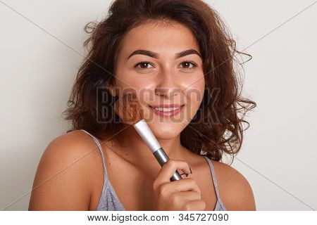 Close Up Portrait Of Energetic Positive Delighted Female Looking Directly At Camera, Holding Makeup 