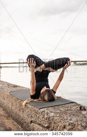 Yoga Meditation And Wellness Lifestyle Concept. Fit Slim Woman Practicing Yoga Exercises Near River 